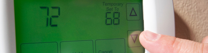 finger pressing down arrow on a thermostat
