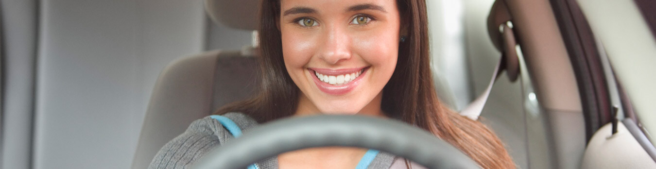 smiling young woman driving car