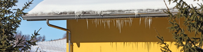 roof covered with snow with icicles hanging off gutter