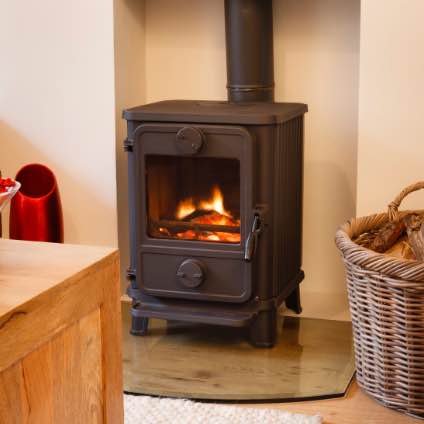 lit wood burning stove behind a table and basket