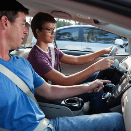 man showing teenager how to drive